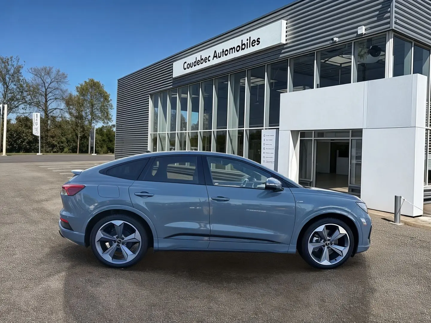 Audi Q4 e-tron gris galet vue de profil côté gauche, avec jantes 19 pouces et lignes fluides de SUV électrique.
