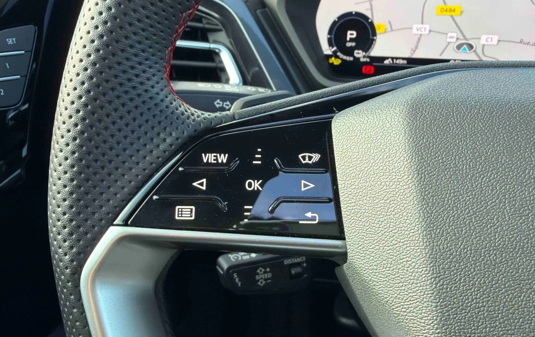 Gros plan sur le volant cuir perforé avec commandes tactiles à gauche et affichage numérique du tableau de bord de l’Audi Q4 e-tron gris galet.