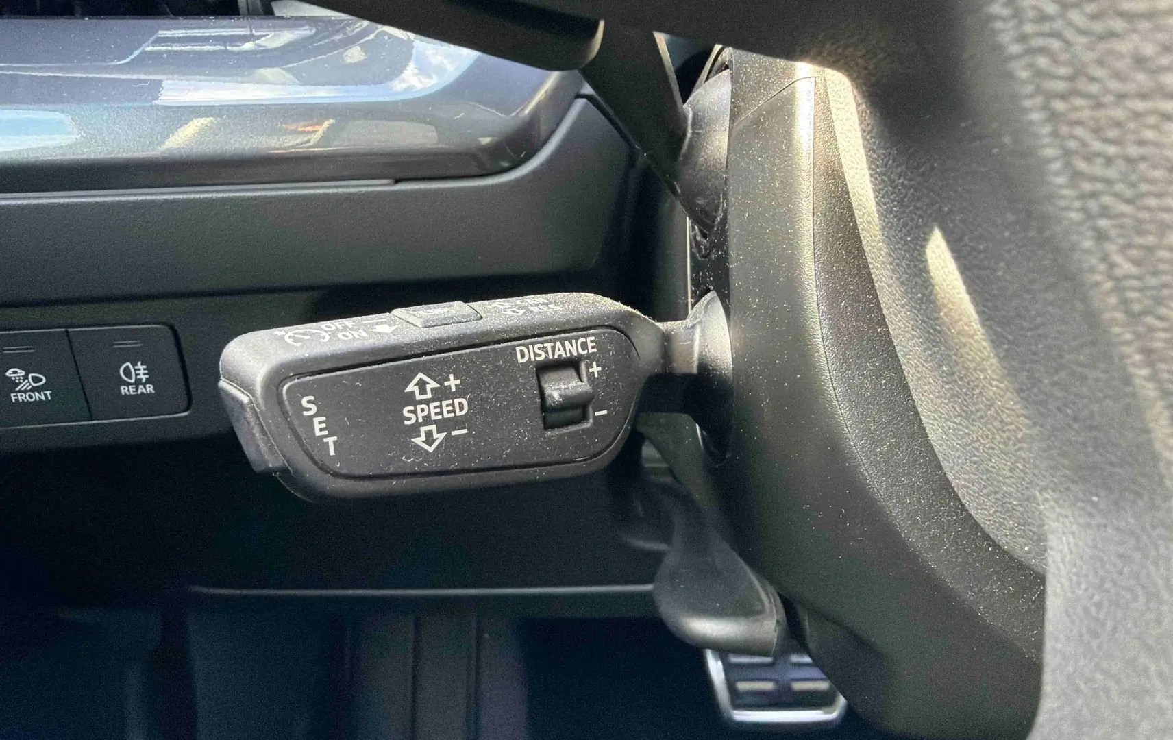 Gros plan sur la commande de régulateur de vitesse au volant d’un Audi Q4 e-tron gris galet 2025.