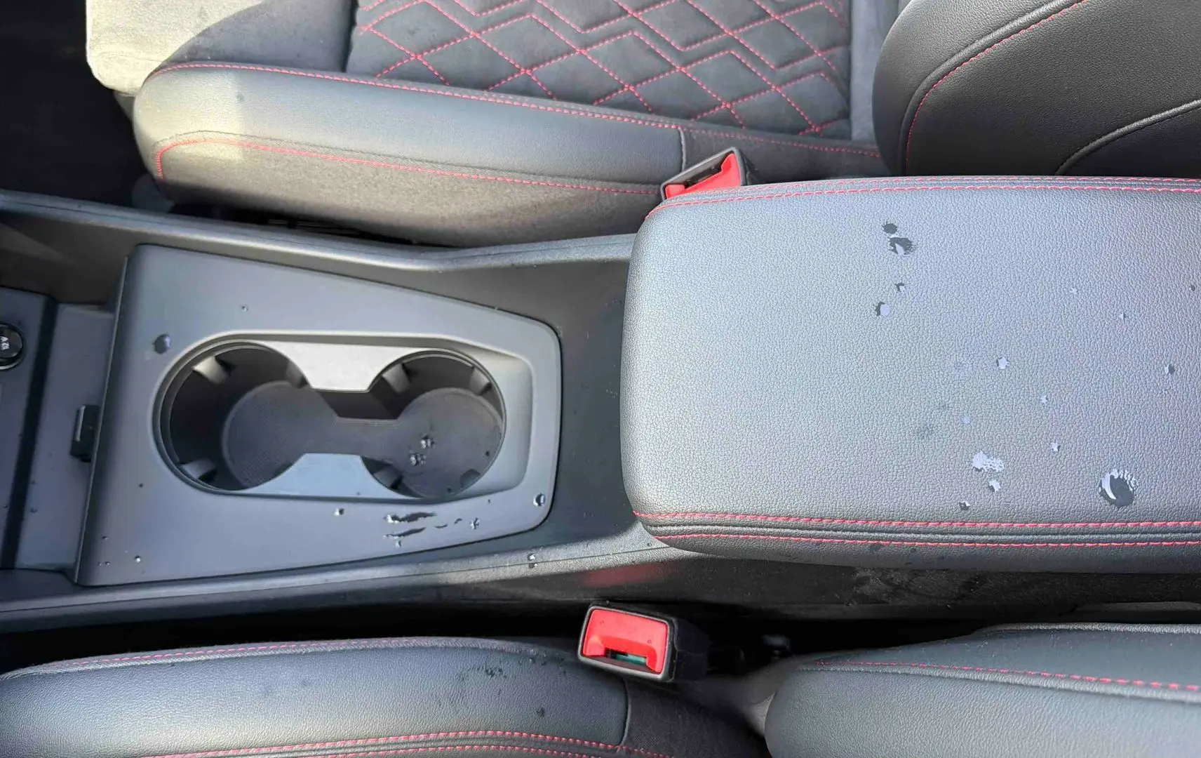 Gros plan sur la console centrale et accoudoir en cuir noir avec surpiqûres rouges de l'Audi Q4 e-tron 2025.