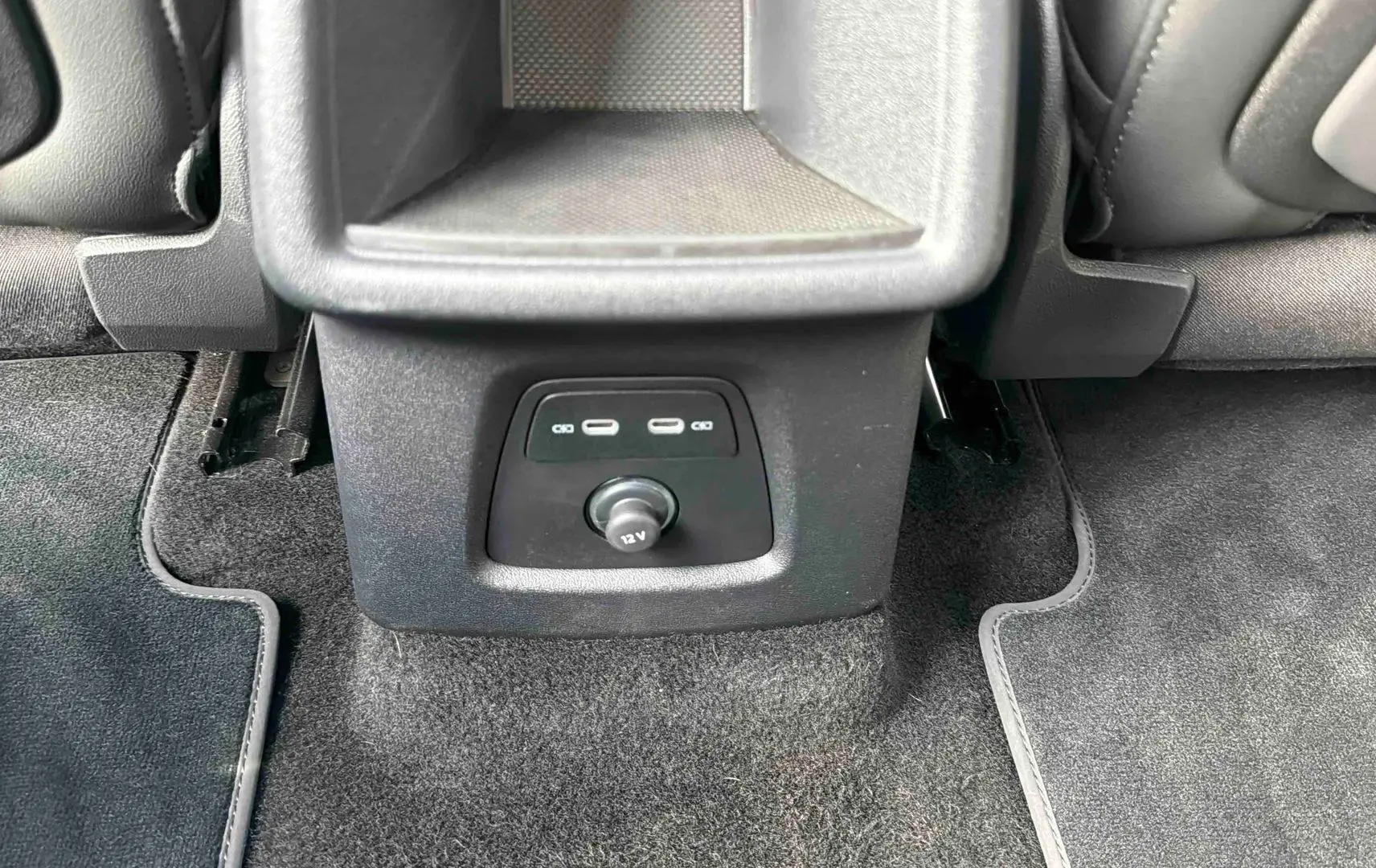 Prise USB et prise 12V au bas de la console centrale arrière, tapis de sol gris dans un Audi Q4 e-tron 2025.