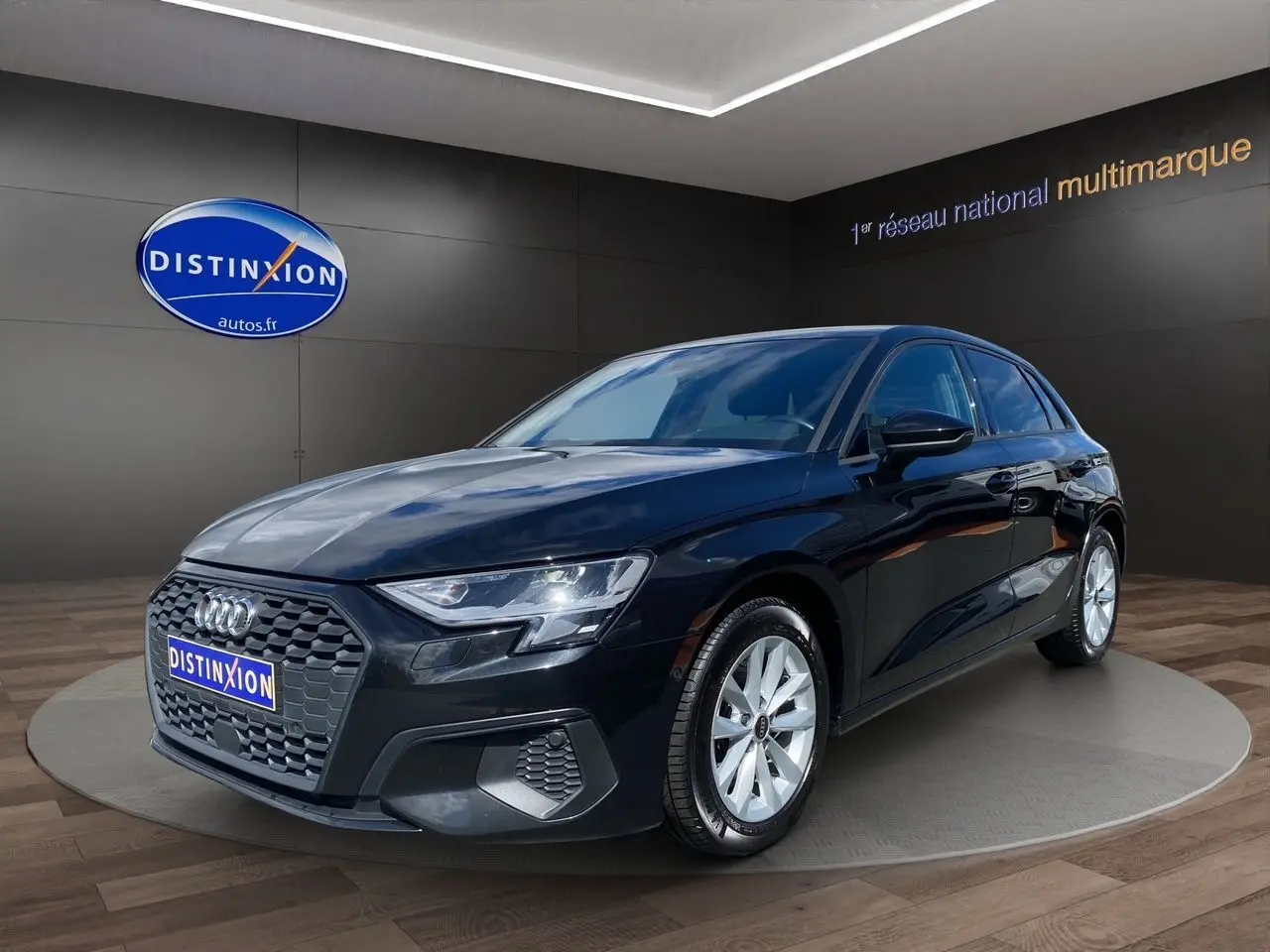 Audi A3 Sportback noir vue 3/4 avant droit, mettant en valeur sa calandre hexagonale et ses jantes argentées.