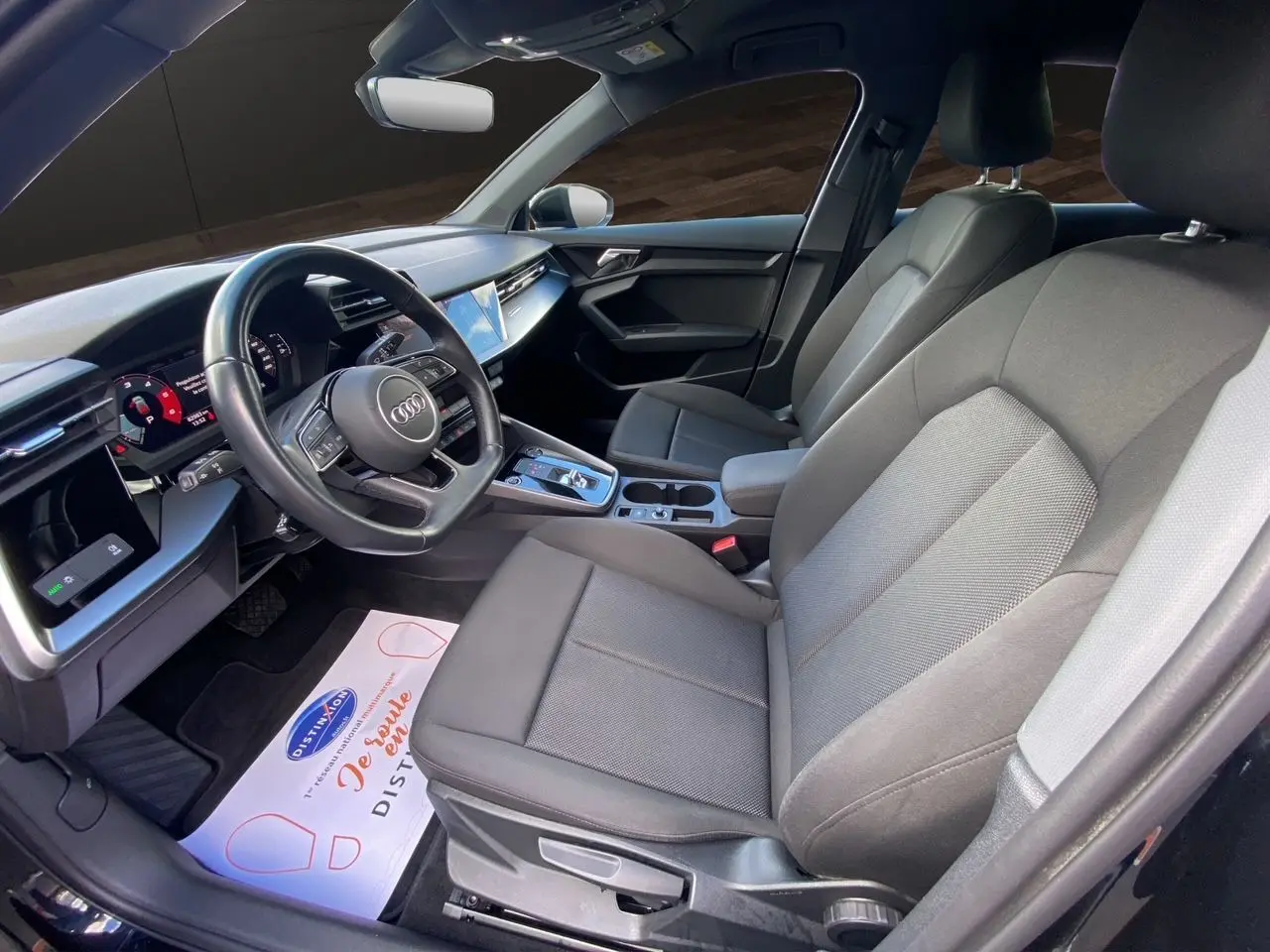 Intérieur noir de l'Audi A3 Sportback 2021 vu côté conducteur, avec tableau de bord digital et sièges tissu.