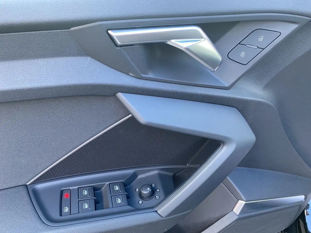 Détail de la porte côté conducteur d'une Audi A3 Sportback noire, montrant les commandes de vitres et de verrouillage.