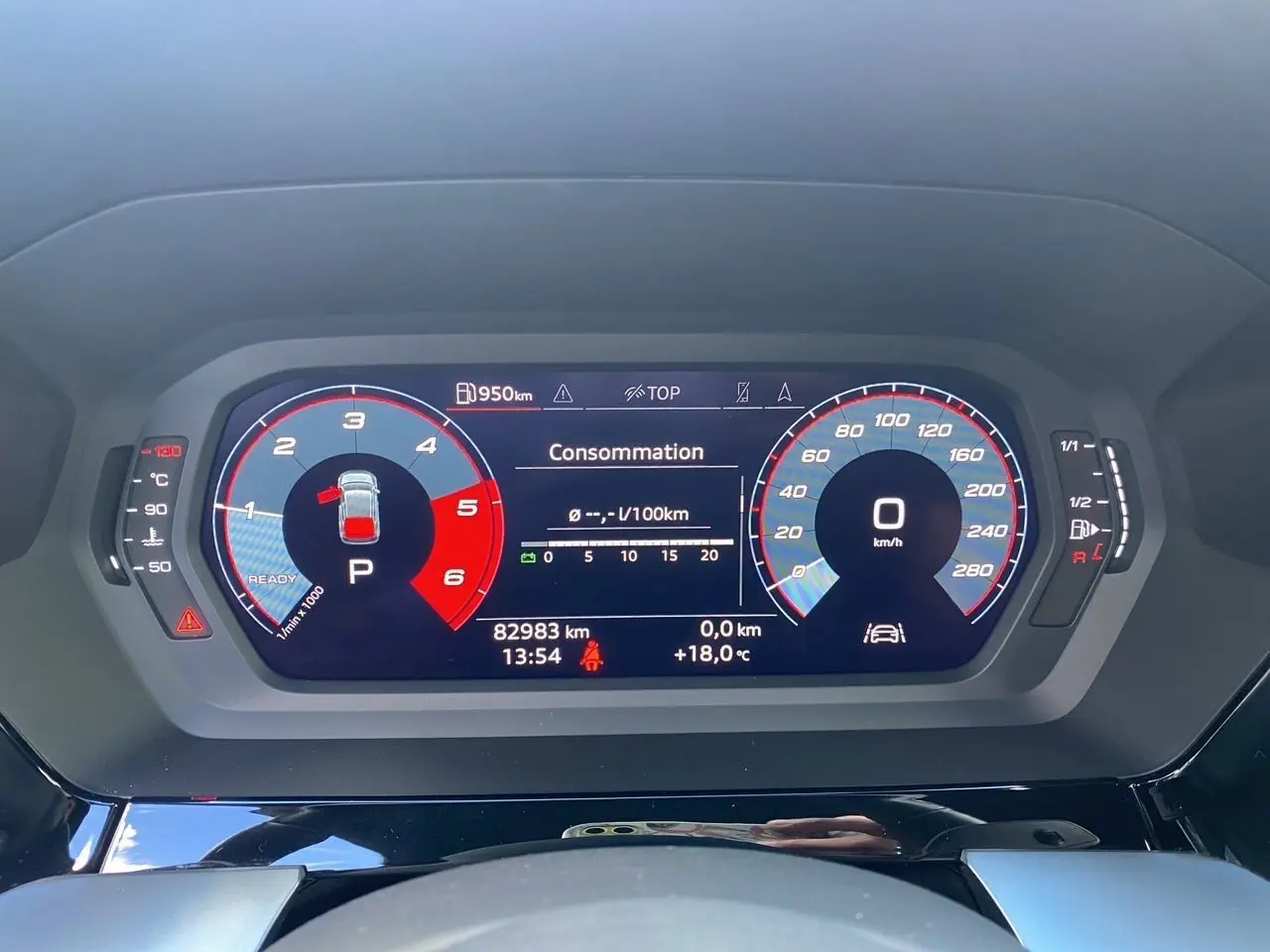 Tableau de bord numérique d'une Audi A3 Sportback noir, affichant consommation et vitesse à 0 km/h.