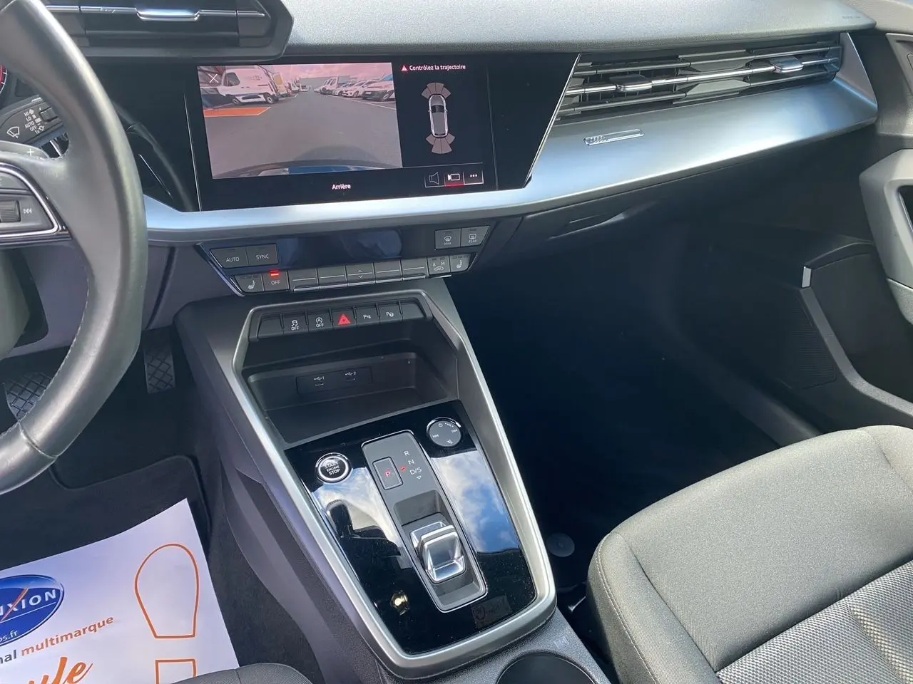 Vue intérieure côté passager de l'Audi A3 Sportback 2021 avec écran caméra de recul et console centrale noire brillante.