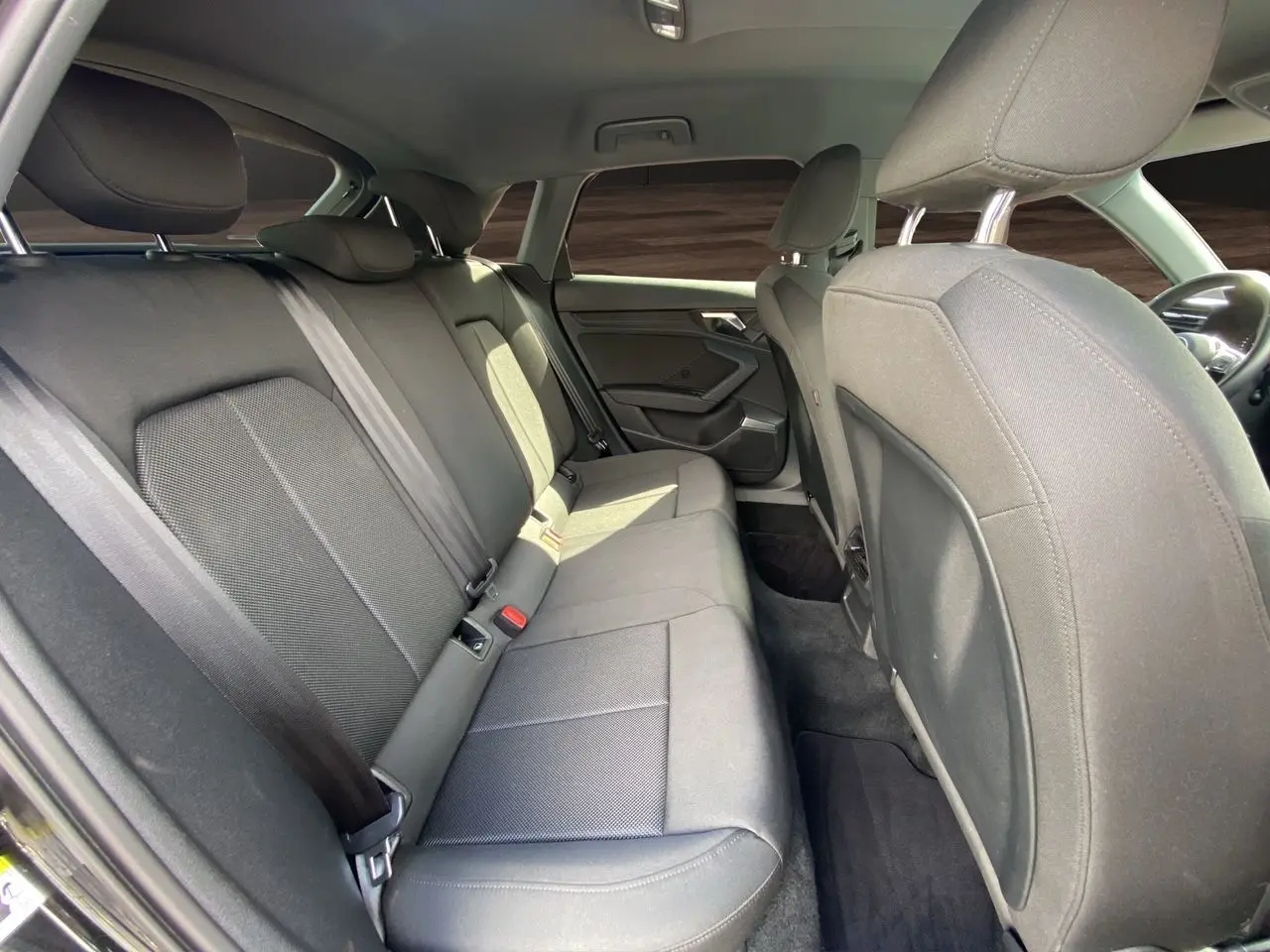 Vue intérieure côté arrière droit de l'Audi A3 Sportback 2021 avec sièges arrière en tissu noir et ceintures de sécurité.