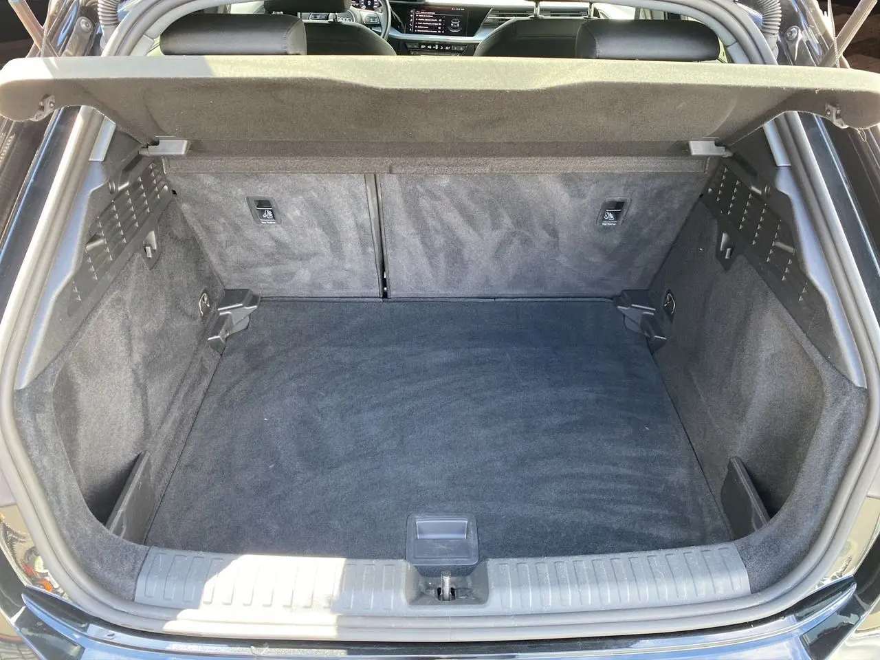 Coffre ouvert vu de l'arrière d'une Audi A3 Sportback noire, montrant un espace de chargement propre et spacieux.