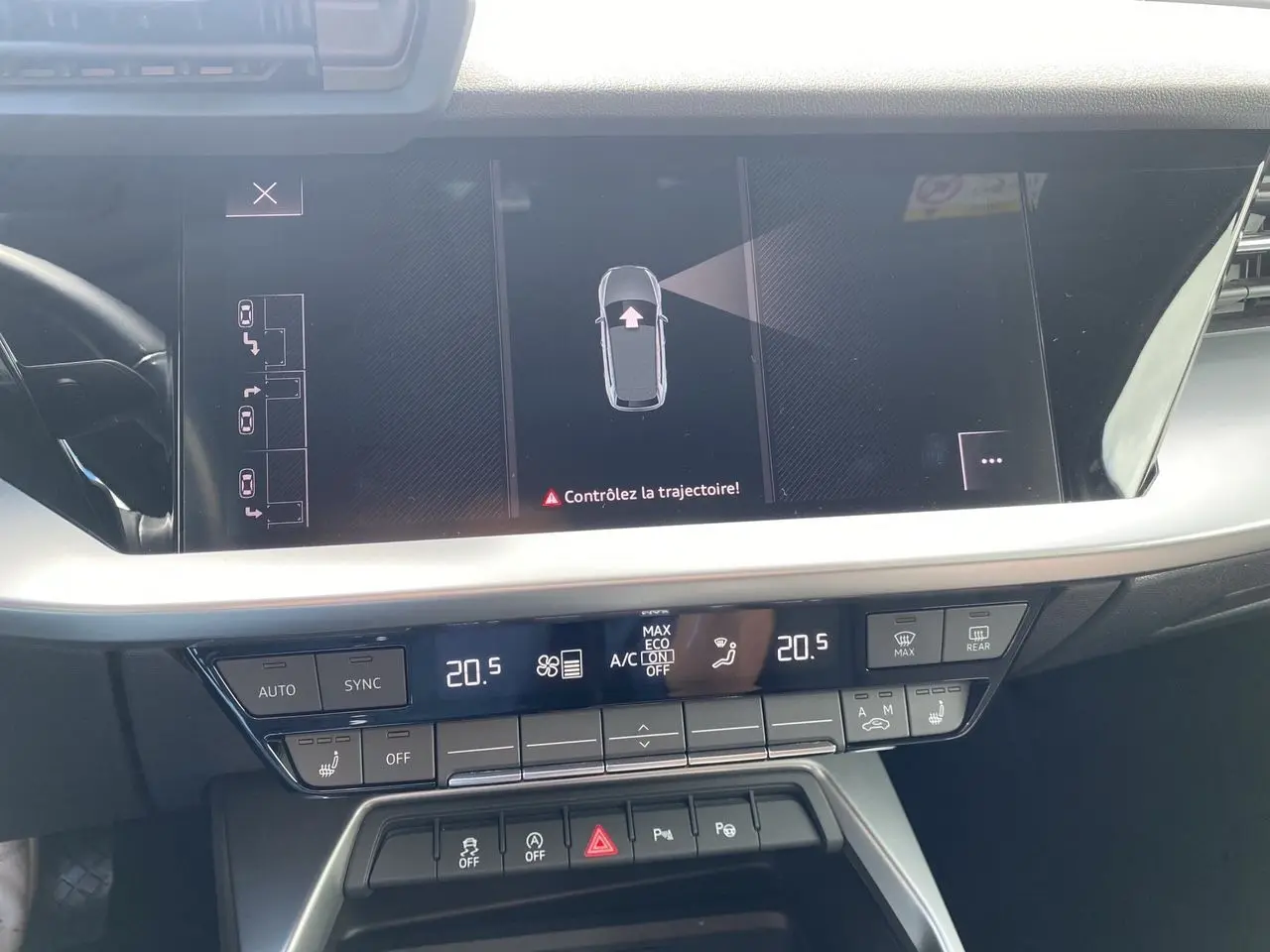 Vue rapprochée de l'écran central et de la console de l'Audi A3 Sportback noire, affichant la caméra de recul et la climatisation.