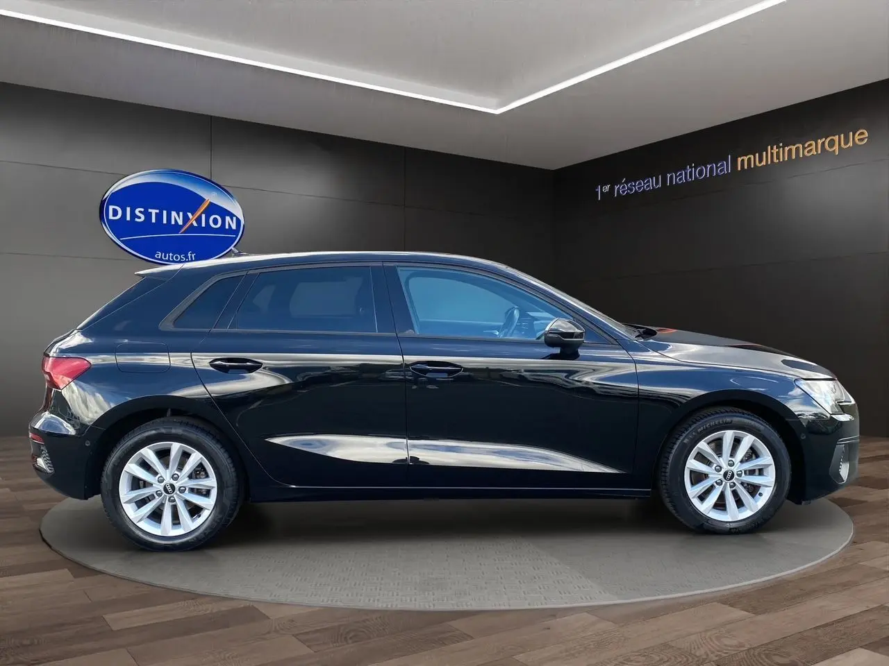 Profil côté gauche d'une Audi A3 Sportback noire 2021, avec jantes argentées et vitres teintées en showroom.