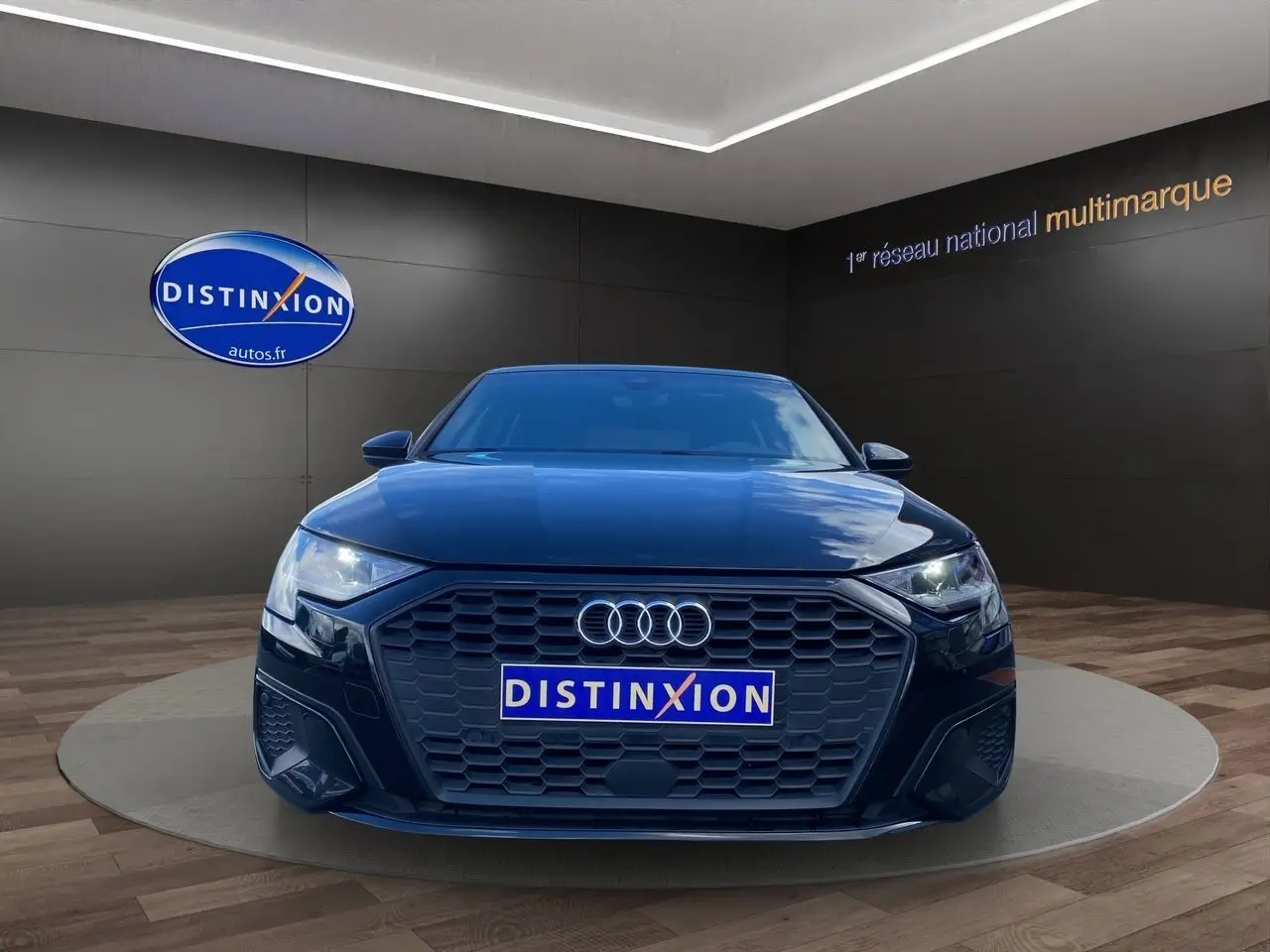 Vue frontale d'une Audi A3 Sportback noire 2021 avec calandre hexagonale et phares LED allumés.