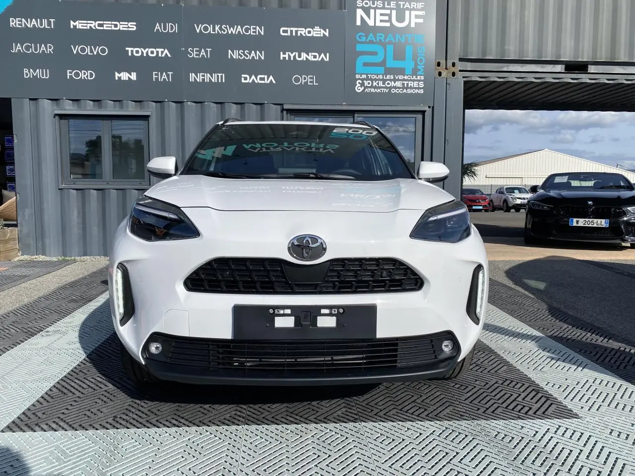 Vue frontale d'une Toyota Yaris Cross blanche pure avec calandre noire et phares LED distinctifs.