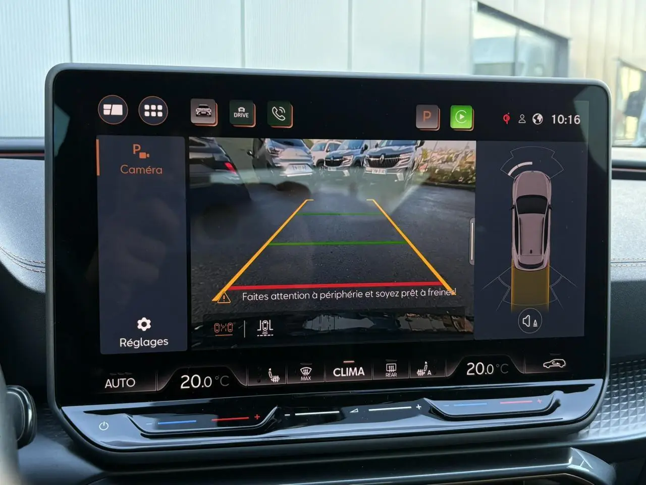 Écran tactile intérieur affichant la caméra de recul avec vue arrière et aides au stationnement du CUPRA Formentor gris.