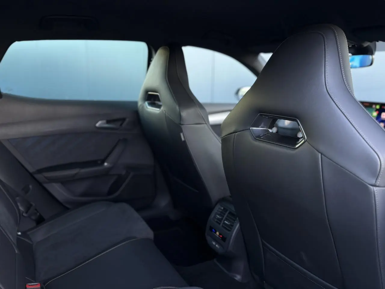 Vue intérieure arrière montrant les sièges baquets noirs en suédine et cuir du CUPRA Formentor 2024 côté gauche.