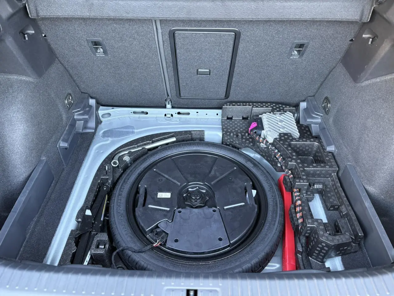 Vue plongeante sur la roue de secours compacte et le rangement gris du coffre du CUPRA Formentor 2024.