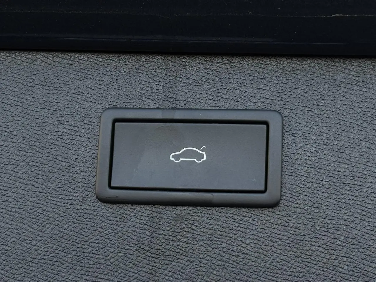 Bouton noir de hayon électrique avec pictogramme blanc, sur fond texturé gris foncé à l'intérieur du CUPRA Formentor.