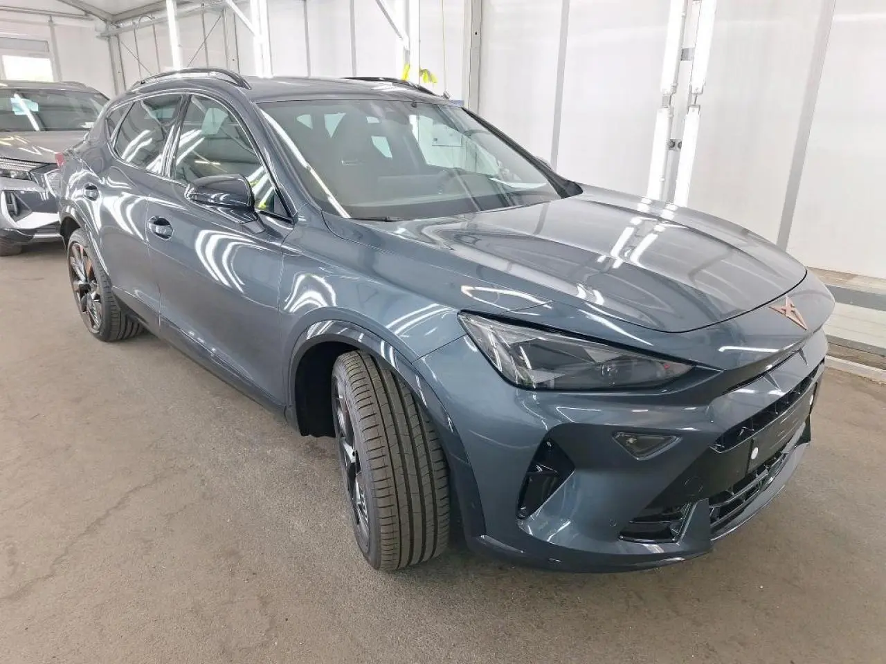 Vue 3/4 avant gauche d'une CUPRA Formentor 2024 gris magnétique avec jantes alliage noires et logo cuivré sur calandre