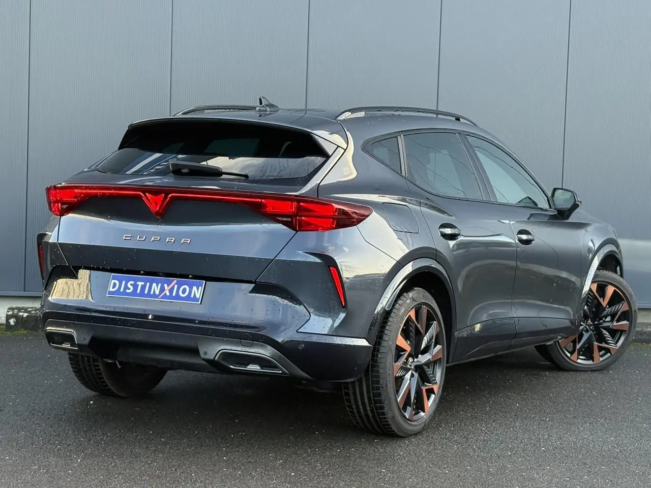 Vue 3/4 arrière droite d'une CUPRA Formentor gris magnétique avec jantes alliage 19'' cuivrées et feux arrière LED triangulaires.