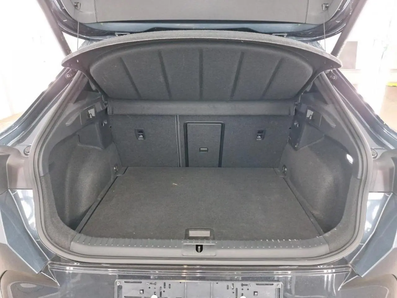 Coffre ouvert vu de l'arrière d'une CUPRA Formentor 2024 gris magnétique avec hayon électrique et intérieur noir.