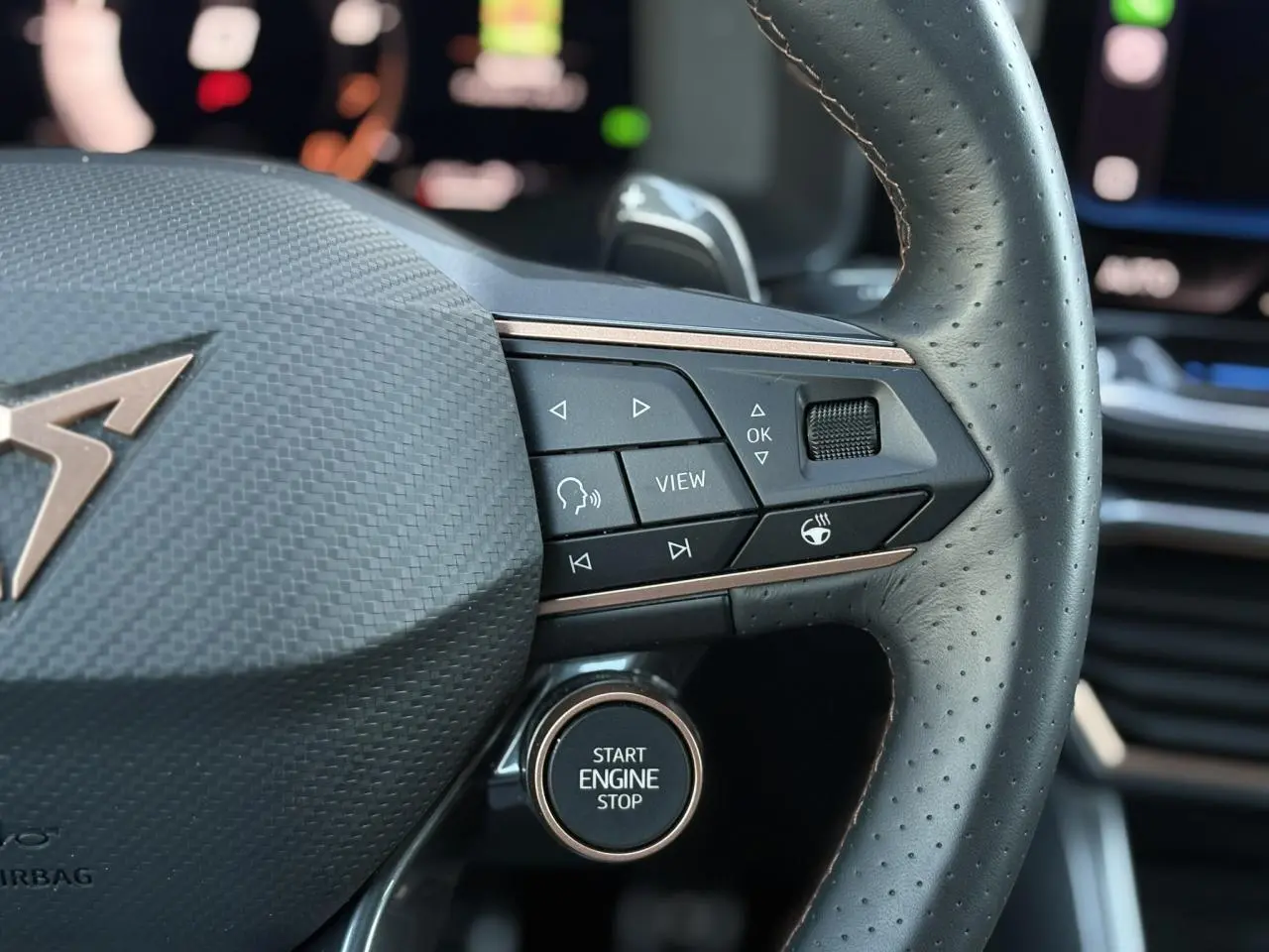 Gros plan sur le volant cuir perforé noir du CUPRA Formentor gris, avec commandes multifonctions et bouton Start Engine Stop.