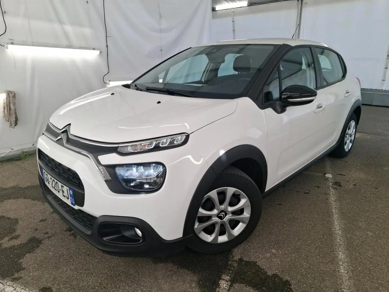 Citroën C3 blanche vue 3/4 avant droit, avec coques de rétroviseurs noires et enjoliveurs 15 pouces.