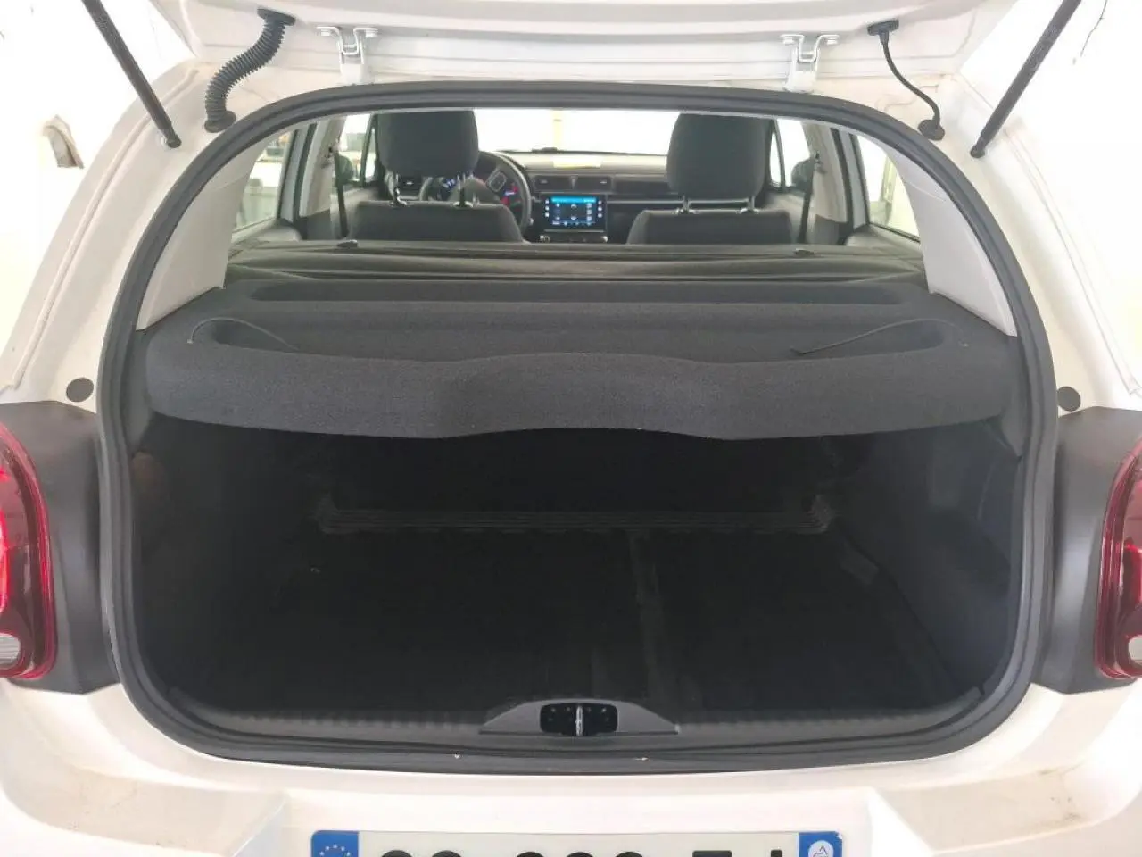 Coffre ouvert d'une Citroën C3 blanche vue de l'arrière, avec tablette cache-bagages et intérieur noir visible.