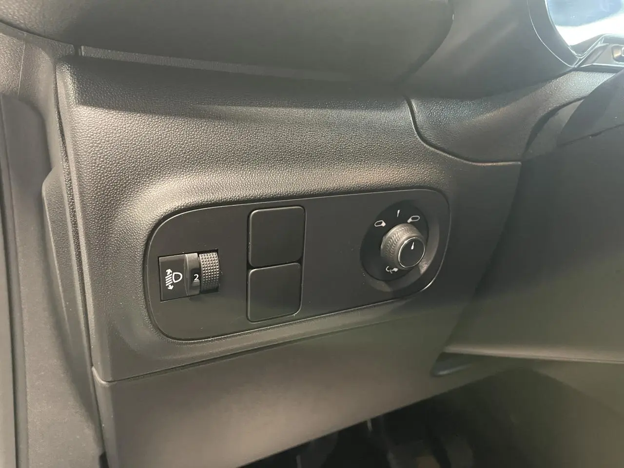 Vue rapprochée des commandes de réglage des phares et des rétroviseurs côté gauche d’un Citroën C3 blanc.