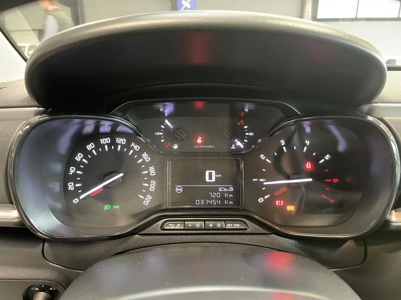 Vue rapprochée du tableau de bord numérique de la Citroën C3 blanche, affichant le compteur et les voyants allumés.