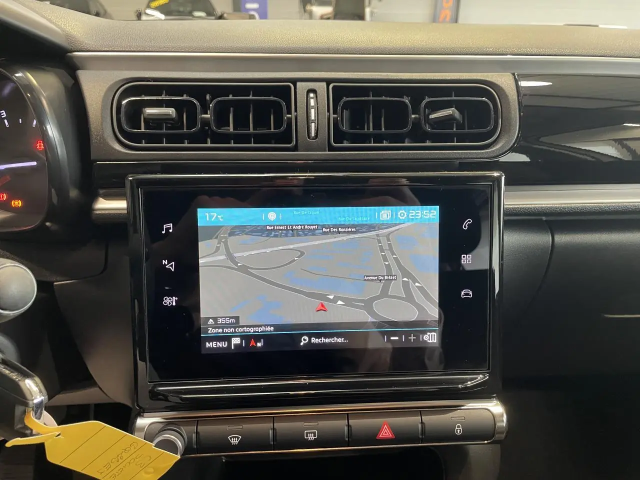 Vue rapprochée du tableau de bord noir brillant de la Citroën C3 2023 avec écran tactile de navigation allumé.