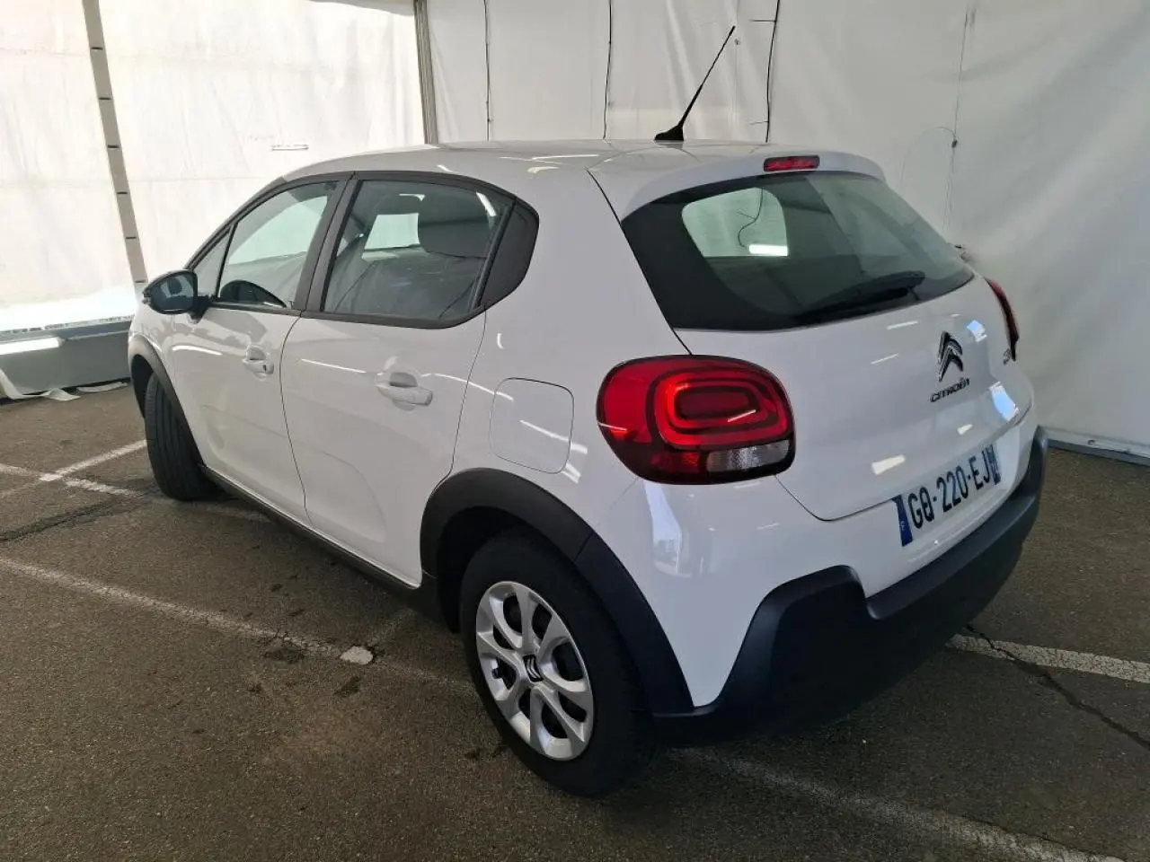 Citroën C3 blanche vue 3/4 arrière droit, avec enjoliveurs 15 pouces et protections noires sur ailes et bas de caisse.