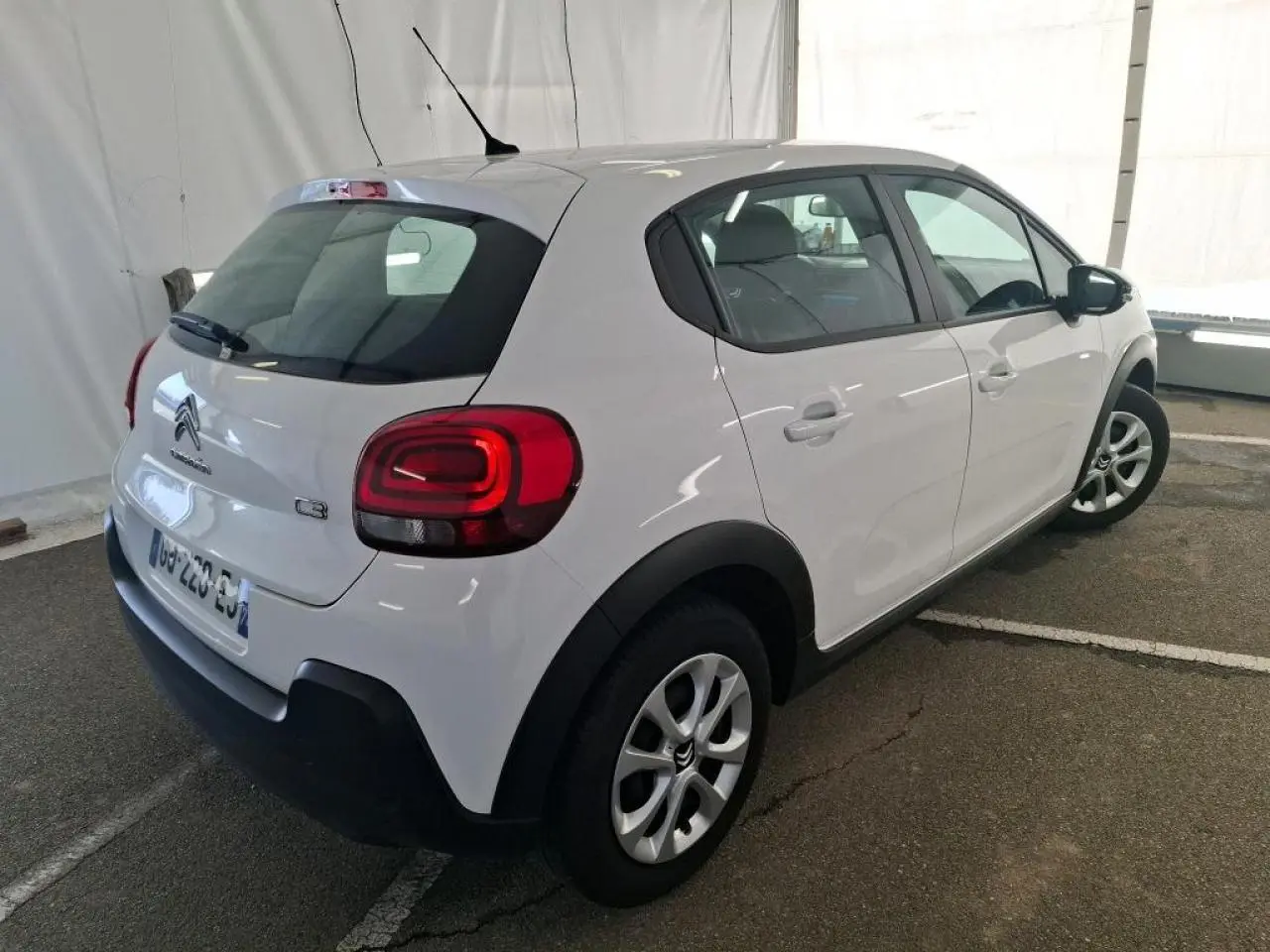 Vue 3/4 arrière droite d'une Citroën C3 blanche avec enjoliveurs 15 pouces et protections noires sur ailes et bas de caisse.