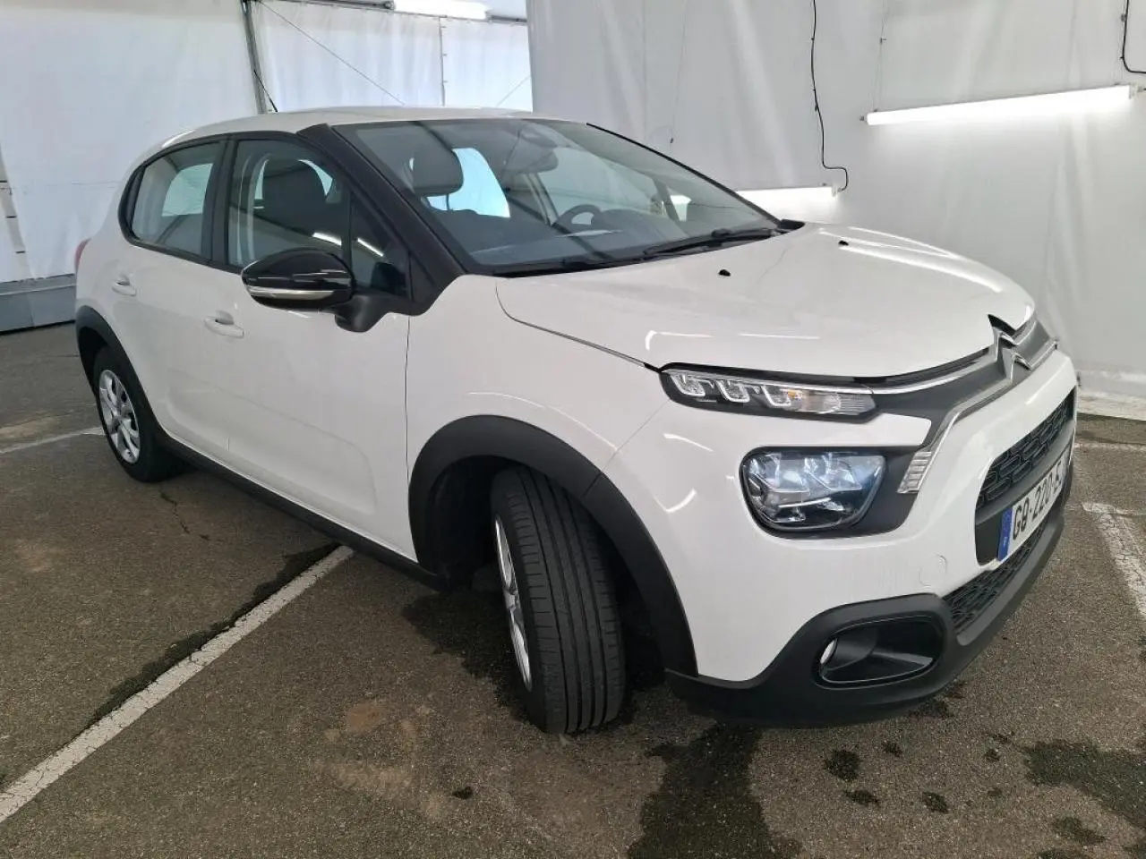 Citroën C3 blanc banquise vue 3/4 avant gauche avec coques de rétroviseurs noires et protections noires.