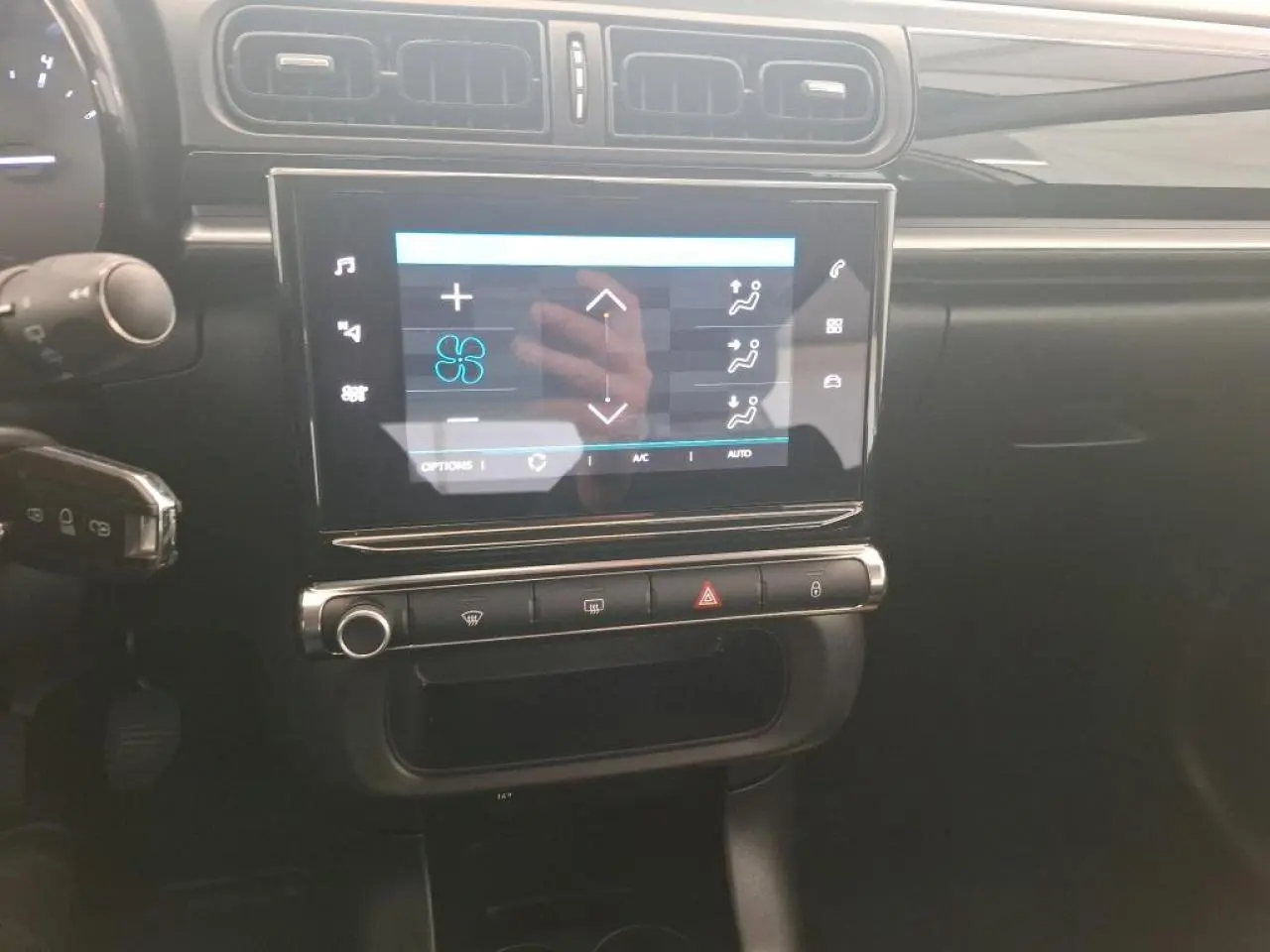 Vue rapprochée de la console centrale noire brillante de la Citroën C3 avec écran tactile affichant la climatisation.