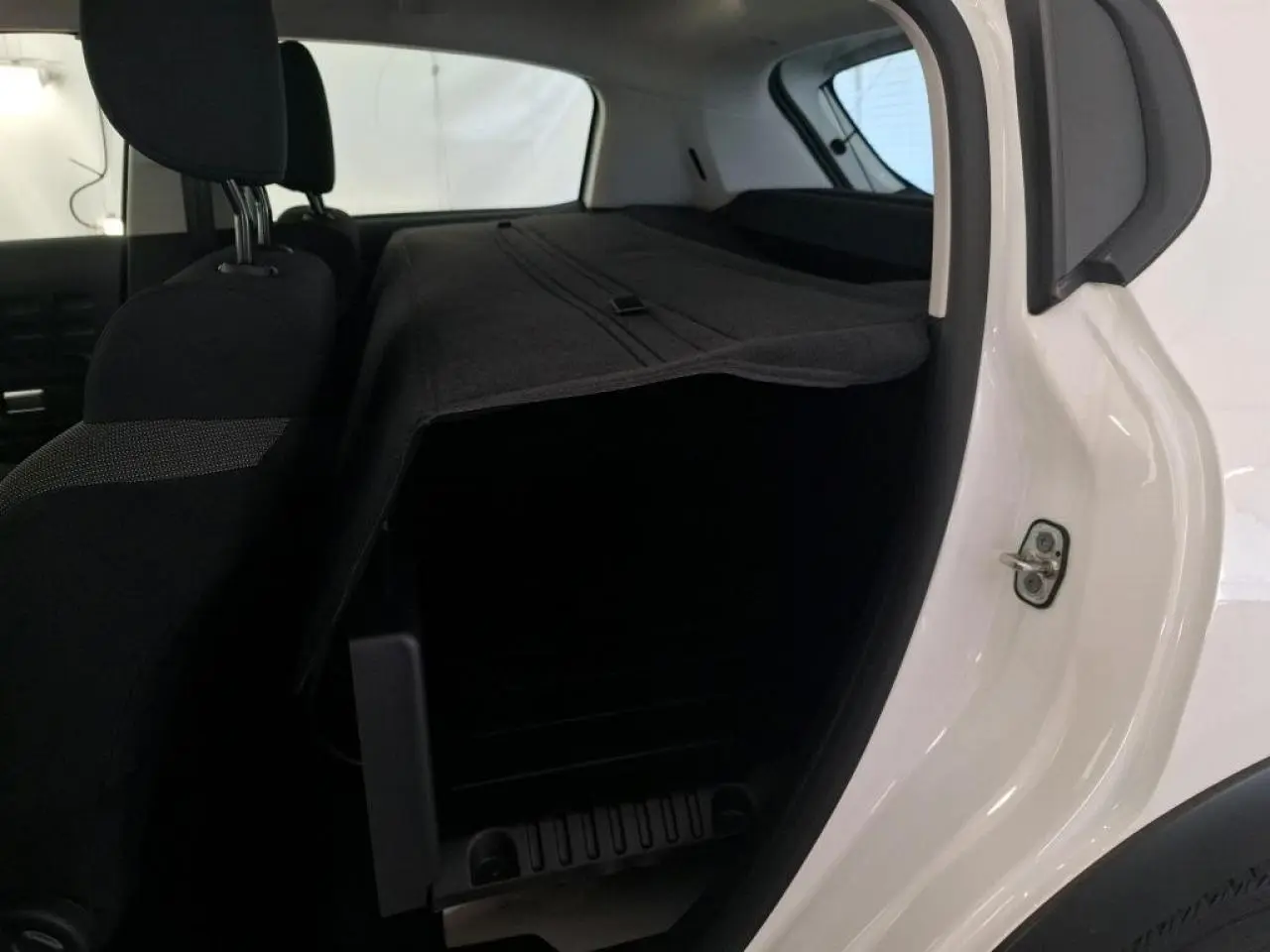 Vue intérieure côté droit du coffre d'une Citroën C3 blanche avec banquette arrière rabattue et cache-bagages déployé.