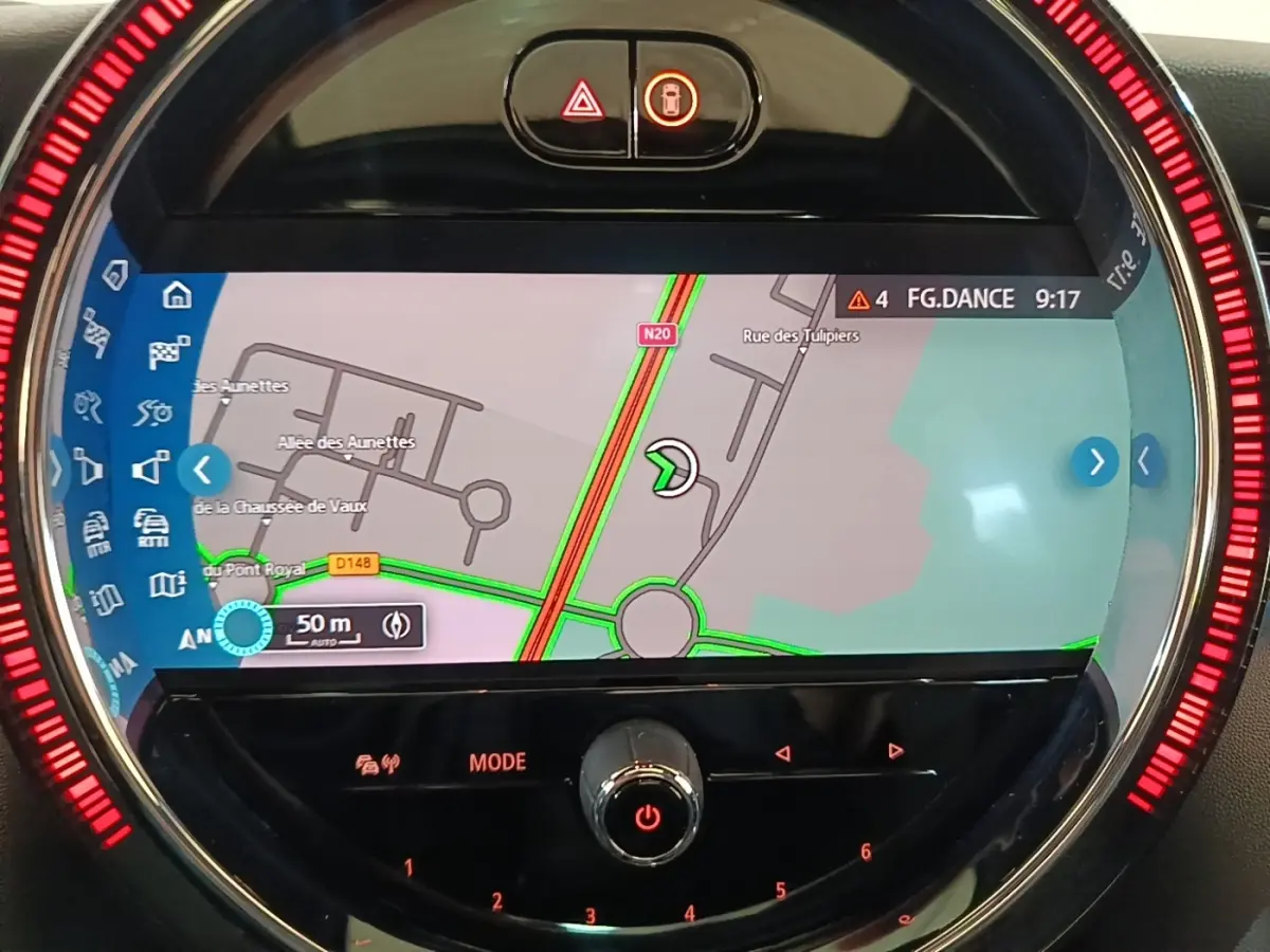 Gros plan sur l'écran central tactile du tableau de bord de la MINI noire, affichant la navigation avec éclairage rouge circulaire.