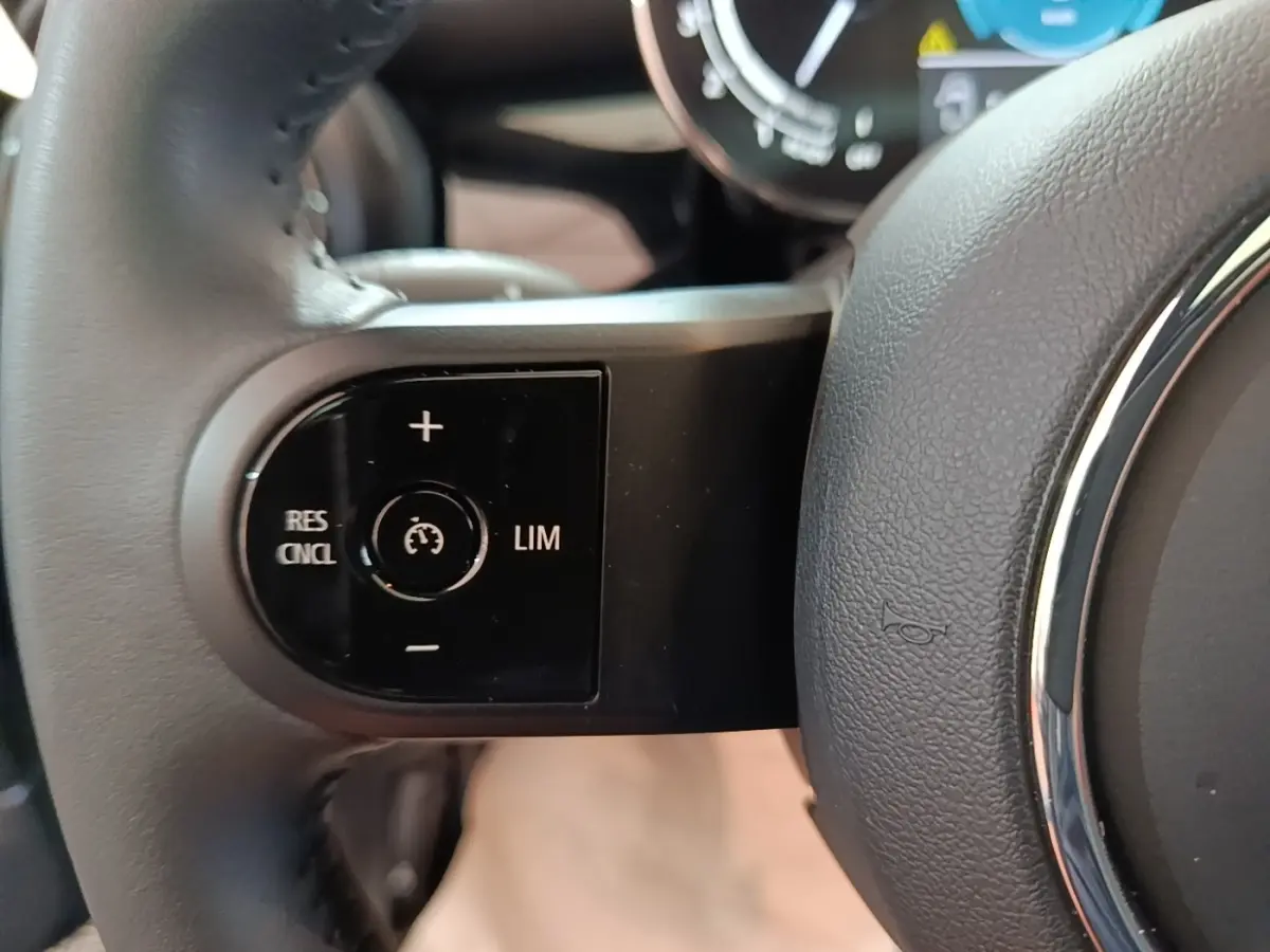 Gros plan sur la commande de régulateur de vitesse côté gauche du volant cuir noir d'une MINI Cooper 2023.