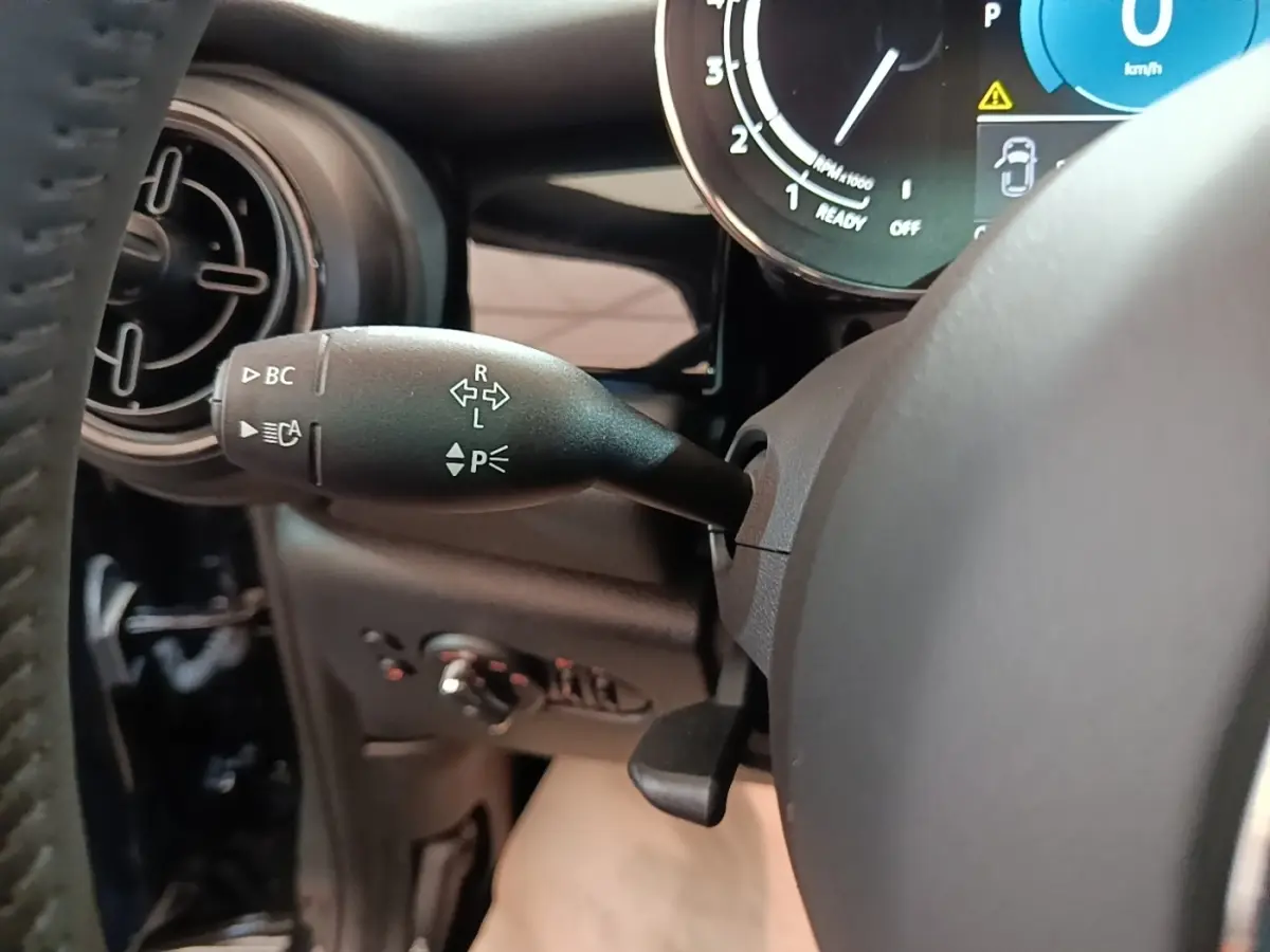 Gros plan sur la manette de clignotant et le combiné d'instruments numérique dans l'habitacle noir d'une MINI Cooper 2023.
