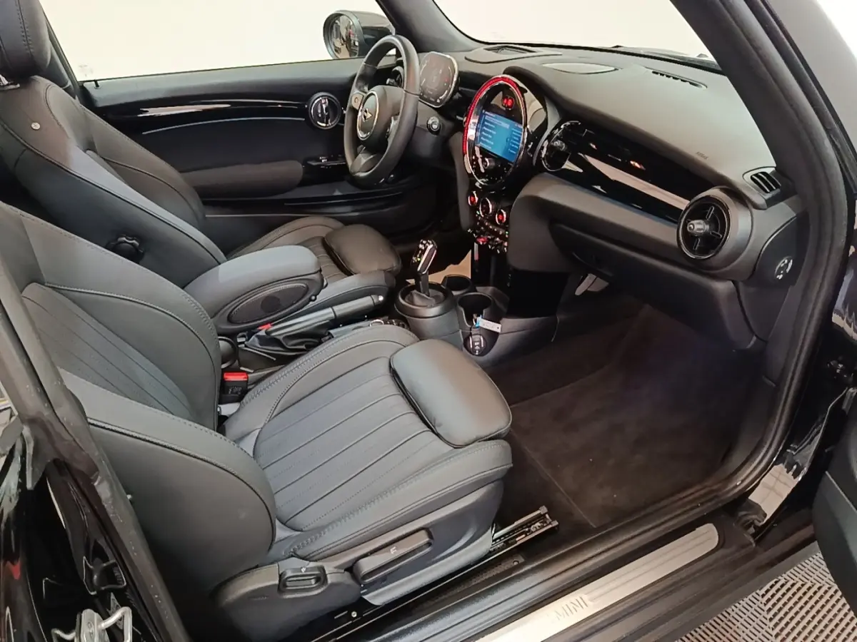 Vue intérieure côté conducteur de la MINI Cooper Edition Premium Plus noire, avec tableau de bord et sièges en cuir noirs.