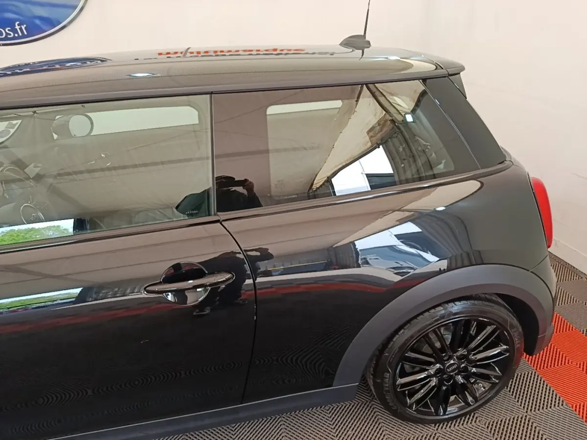 Vue latérale droite d'une MINI Cooper Edition Premium Plus noire avec jantes alliage noires brillantes et toit noir.