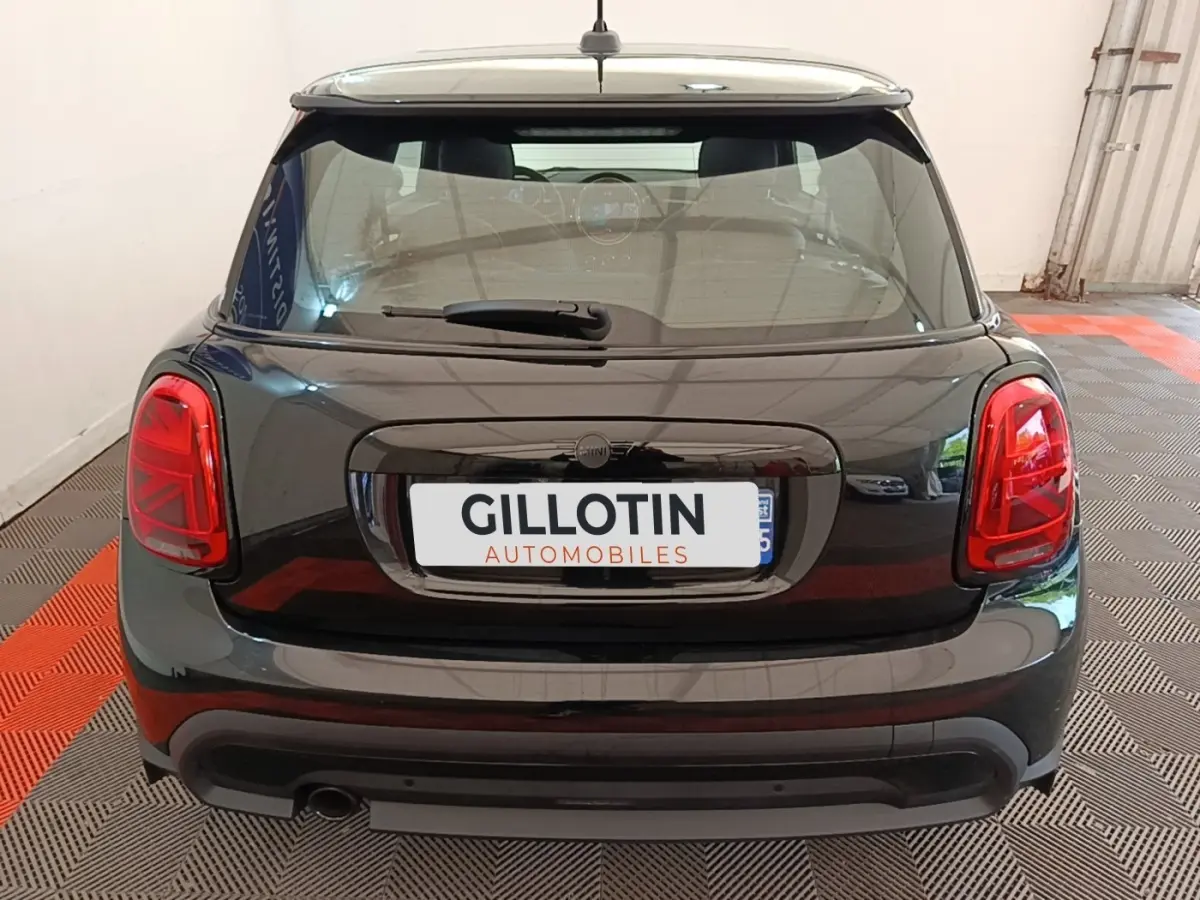 Vue arrière d'une MINI Cooper Edition Premium Plus 2023 noire avec feux arrière rouges et toit blanc.