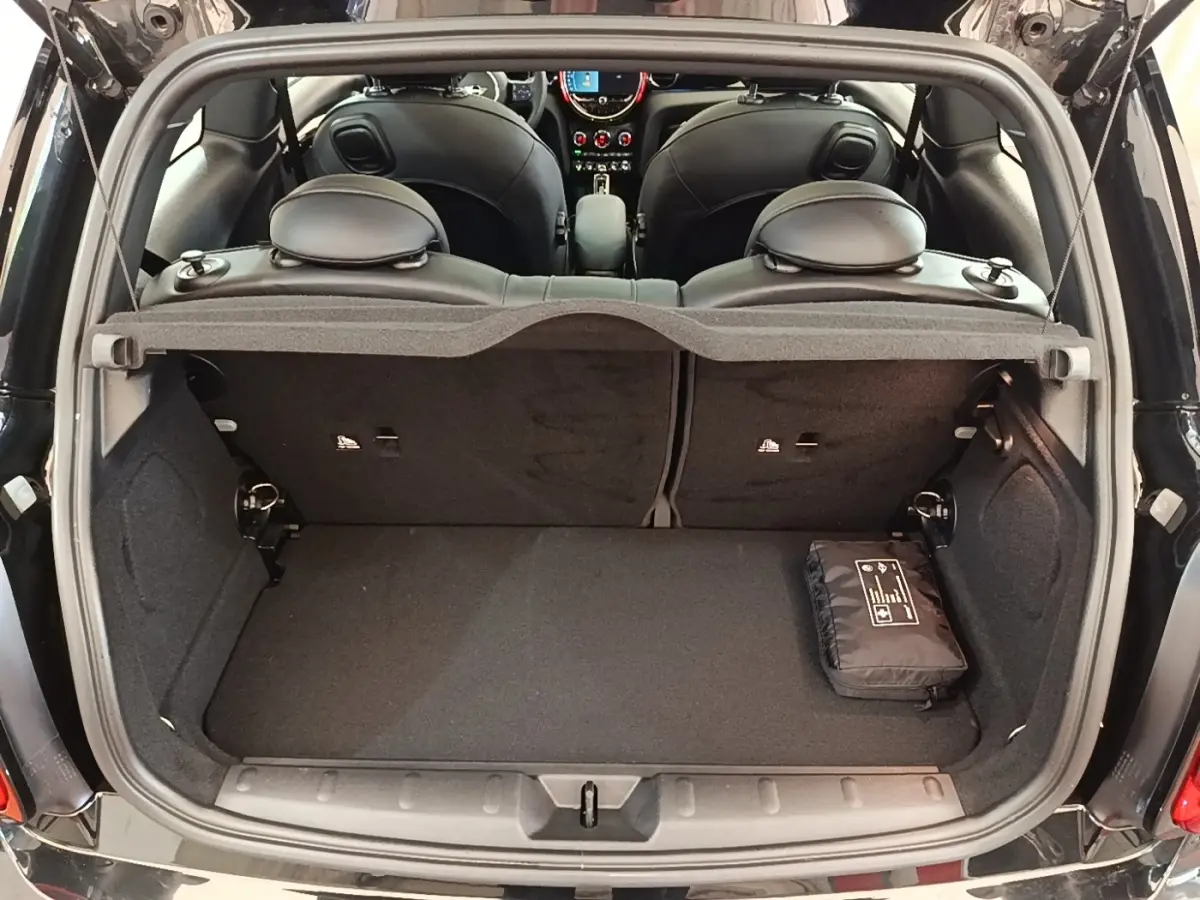 Vue arrière du coffre ouvert d'une MINI Cooper Edition Premium Plus noire, montrant l'intérieur et la banquette arrière.