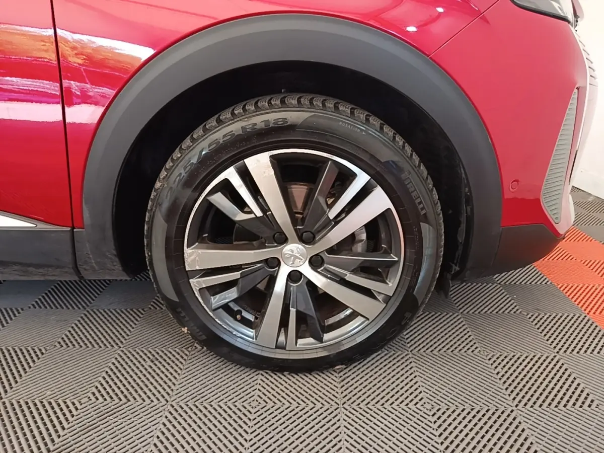 Gros plan sur la roue avant gauche du Peugeot 3008 rouge, avec jante alliage bicolore et pneu Pirelli.