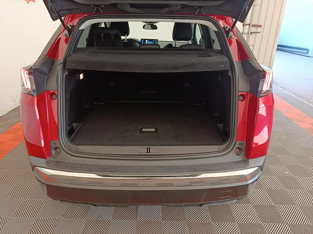 Vue arrière ouverte du coffre d’un Peugeot 3008 rouge, montrant un espace de chargement spacieux et la tablette cache-bagages.