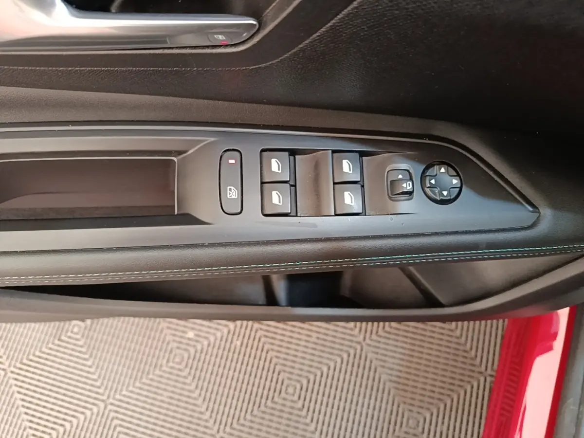 Gros plan sur la commande des vitres électriques et rétroviseurs sur la porte côté conducteur d’un Peugeot 3008 rouge.