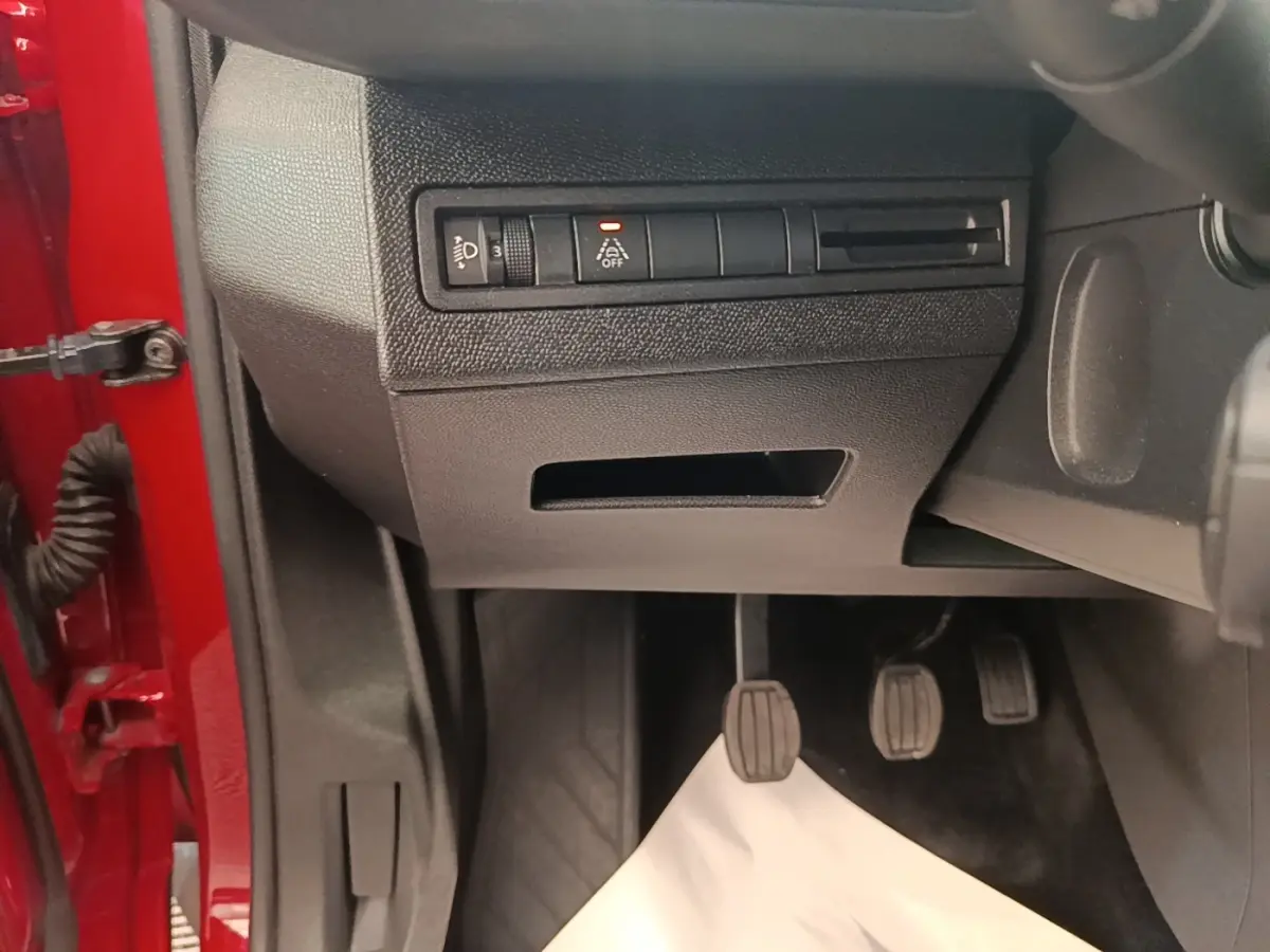 Vue intérieure côté conducteur du Peugeot 3008 rouge, montrant les pédales et les commandes sous le tableau de bord.