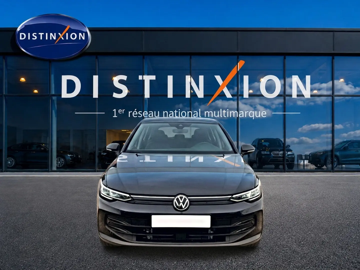 Vue frontale d'une Volkswagen Golf noire 2026 garée devant une vitrine avec logo Distinxion.