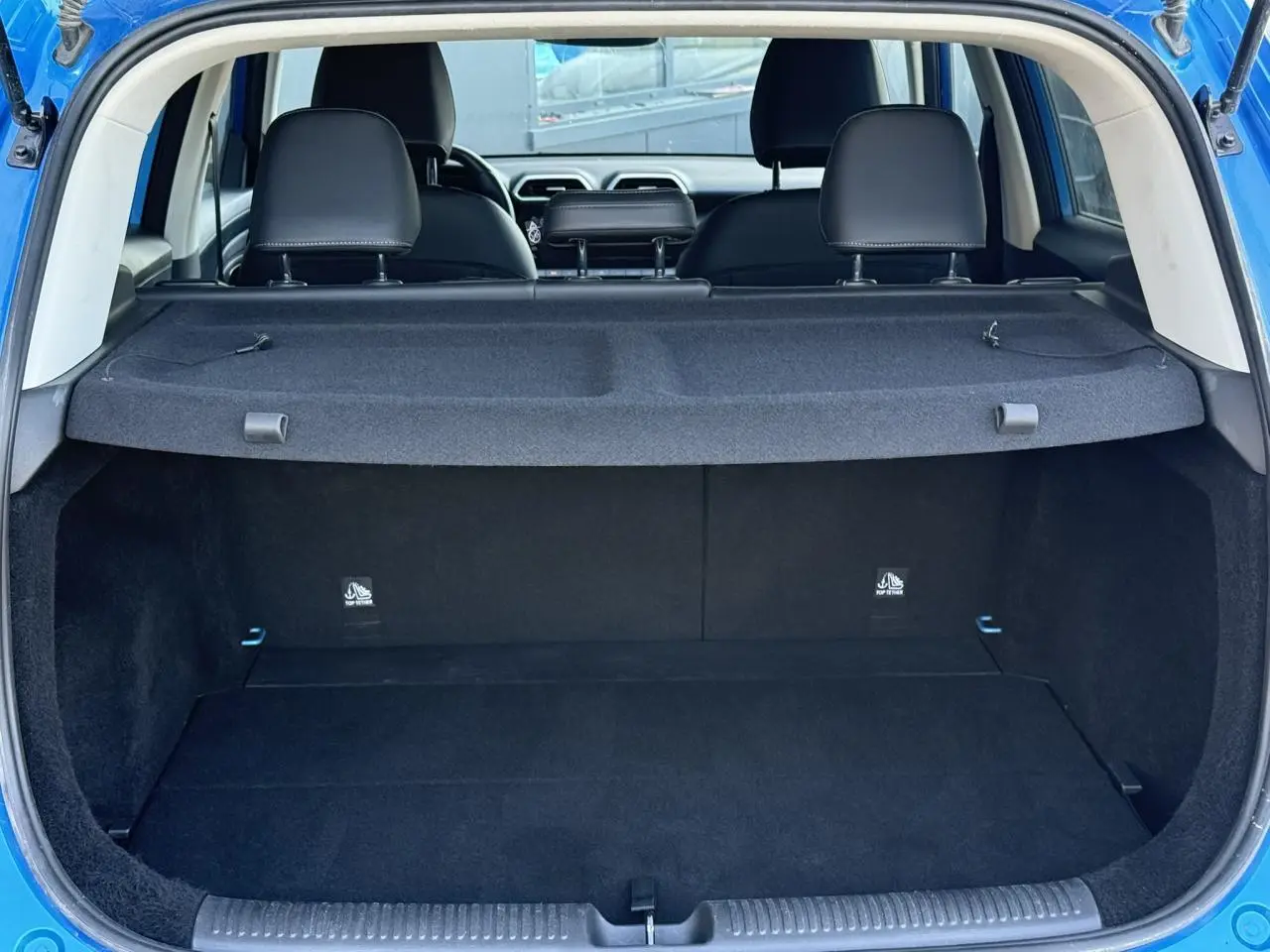 Vue arrière du coffre ouvert du MG ZS 1.5 Hybrid+ 197 Luxury bleu Como, avec banquette arrière et cache-bagages visibles.