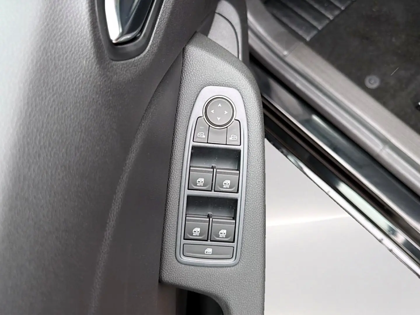 Gros plan sur les commandes des vitres électriques côté gauche d’une Renault Clio V noire, intérieur sombre.