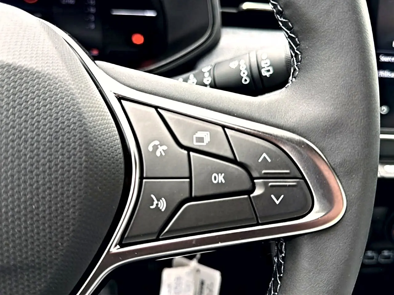 Gros plan sur les commandes multifonctions à droite du volant noir de la Renault Clio V 1.0 TCe 90 Evolution.
