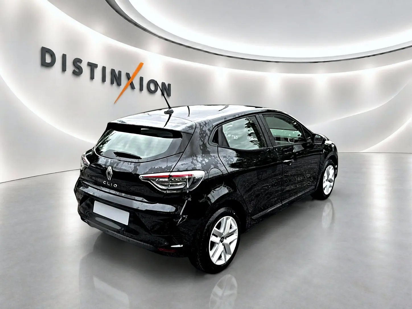Renault Clio V noire vue en 3/4 arrière droit, avec feux arrière LED et becquet sur fond blanc lumineux.